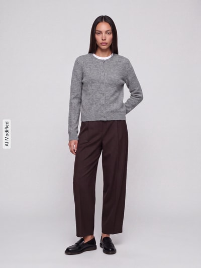 Frauenmodel trägt graue Regular Fit Strickjacke mit Woll-Anteil Modell 'MALOU' von PIECES, braune Hose, neutrale Farben, Ganzkörperansicht von vorne, KI-modifiziertes Bild.