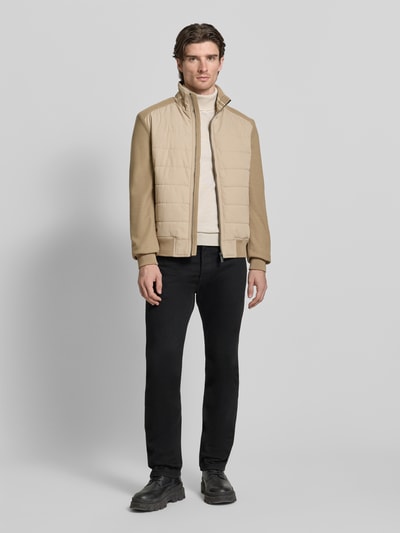 Männermodel trägt Jacke mit Stehkragen von Christian Berg Men in Beige, Regular Fit, Reißverschlusstaschen, Ganzkörperansicht von vorne.