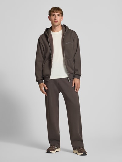 Männermodel trägt Relaxed Fit Sweatjacke aus Baumwoll-Mix mit Label-Detail von REVIEW, braun, elastische Abschlüsse, Känguru-Tasche, Kapuze, Ganzkörperansicht von vorne.