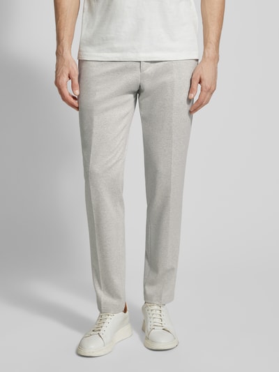 Männermodel trägt helle, gerade geschnittene Hose, glatte Textur, schlichte Form, Nahaufnahme Beinbereich, neutrale Umgebung.