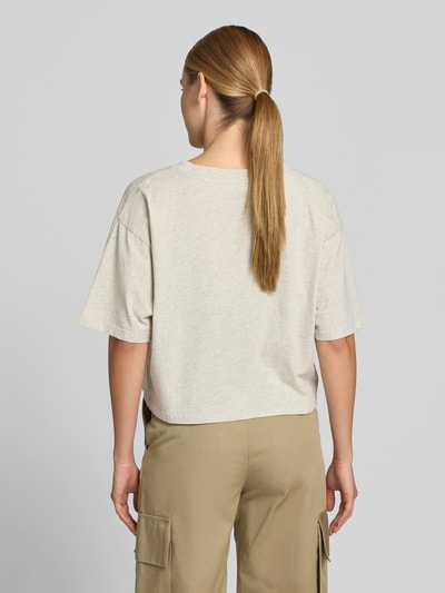 Frauenmodel trägt Oversized T-Shirt mit Logo-Print von Anine Bing aus reiner Baumwolle, Oversized-Fit, Cropped, Halbarm, Rückenlänge 47 cm, Ganzkörperansicht Rückansicht.