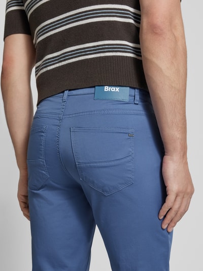 Męski model nosi Slim Fit Stoffhose mit Lyocell-Anteil Modell 'Cadiz' od BRAX w niebieskim kolorze, 5 kieszeni, elastyczna mieszanka bawełny i lyocellu, szerokość w rozmiarze 32/32: 107 cm, długość wewnętrzna nogawki: 81 cm, zapięcie na guzik i zamek błyskawiczny, widok na całe plecy.