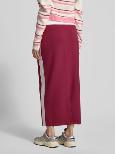 Frauenmodel trägt Straight Fit Midirock mit Logo-Print von Marc Cain in Dunkelrot mit weißen Details, elastischer Bund, Ganzkörperansicht Rückansicht.