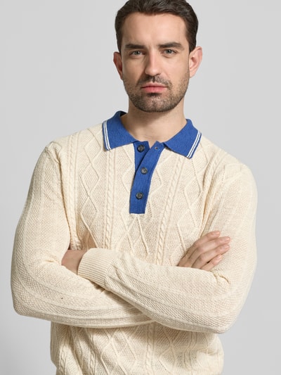 Männermodel trägt Strickpullover aus Leinen-Mix mit Polokragen von Gant, krój slim fit, beżowy, niebieski kołnierzyk, mieszanka lnu z dodatkiem jedwabiu, długość tyłu w rozmiarze M: 68 cm, długość rękawa w rozmiarze M: 70 cm, zapięcie na guziki, tekstura dzianiny, Nahaufnahme Oberkörper.