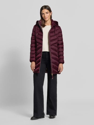 Modelka kobieca ma na sobie Steppmantel mit Zweiwege-Reißverschluss od Christian Berg Woman Selection w kolorze bordowym, krój slim fit, kaptur z troczkiem, boczne kieszenie na suwak, faktura pikowana, przód z dwukierunkowym zamkiem, szerokość w rozmiarze 36: 48 cm, długość pleców: 83 cm, szerokość ramion: 40 cm, długość rękawa: 65 cm, widok całofigurowy z przodu.