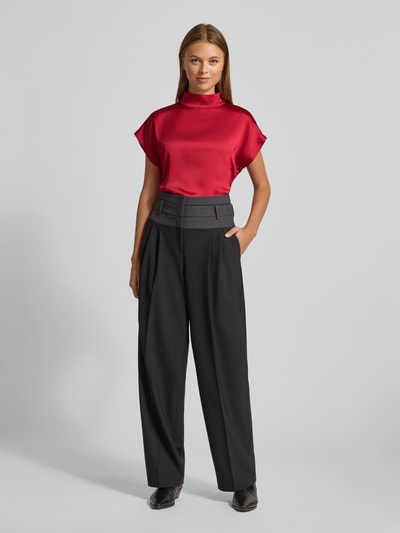 Frauenmodel trägt Relaxed Fit Blusenshirt mit Mock Neck Modell 'CANELI' von HUGO in glänzendem Satin, Ganzkörperansicht von vorne.
