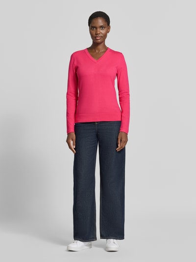 Frauenmodel trägt Pullover aus Viskose-Mix mit V-Ausschnitt von Christian Berg Woman, gerade geschnitten, leuchtendes Pink, Ganzkörperansicht von vorne.
