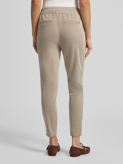 Frauenmodel trägt Slim Fit Stoffhose mit elastischem Bund Modell 'Kate' von ICHI aus Baumwoll-Mix, beige Farbe, Paspeltaschen, Ganzkörperansicht Rückansicht.