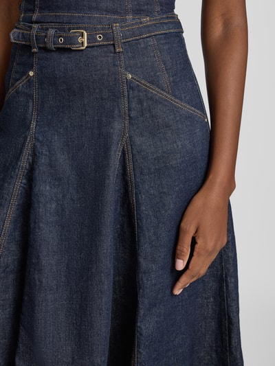Frauenmodel trägt Jeansrock mit Gürtel Modell 'RAYNE' von GUESS, dunkles Blau, Baumwoll-Mix, sichtbare Nähte, Nahaufnahme Oberkörper.