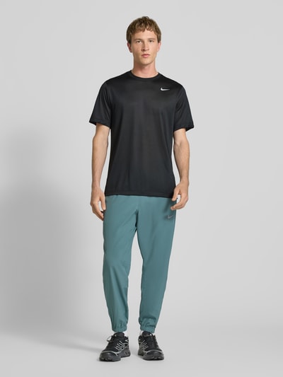 Męski model nosi T-Shirt mit Logo-Print und Rundhalsausschnitt von NIKE TRAINING, czarny kolor, krój regular fit, długość tyłu w rozmiarze M: 66 cm, widok całej sylwetki od przodu.