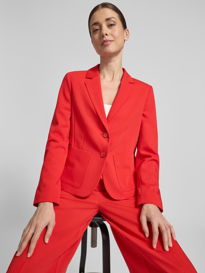 Kobiece modelka nosi Slim Fit Blazer mit Reverskragen von More & More, mieszanka materiałów z dodatkiem wiskozy, krój slim fit, kołnierz z połami, listwa guzikowa, nakładane kieszenie, długość tyłu w rozmiarze 36: 55 cm, szerokość w rozmiarze 36: 40 cm, długość rękawów w rozmiarze 36: 61 cm, intensywna czerwień, gładka struktura, całkowity widok z przodu