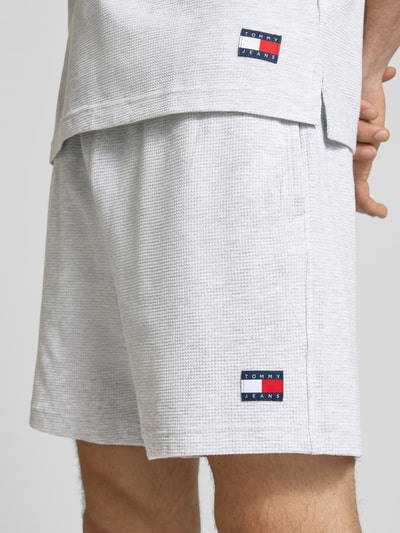 Männermodel trägt Regular Fit Poloshirt aus reiner Baumwolle von Tommy Jeans, Optik: Unifarben, Jersey, Logo-Stitching, Nahaufnahme Oberschenkel.