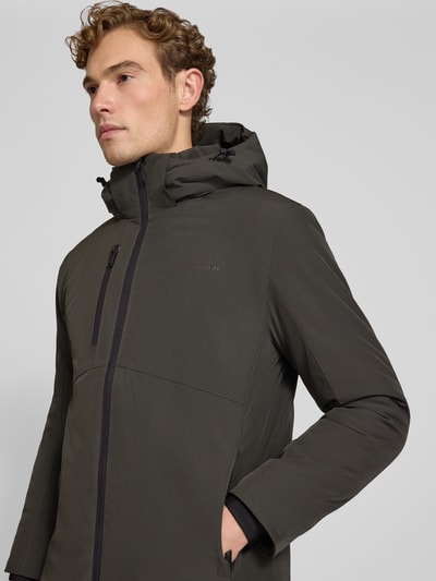 Męski model nosi Regular Fit Parka mit Logo-Print von Lindbergh z elastycznej mieszanki materiałów, kaptur z tunelem, napoleońska kieszeń, zamek błyskawiczny, ciemny kolor, gładka tekstura, Szerokość ramion w rozmiarze M: 50 cm, Szerokość klatki piersiowej w rozmiarze M: 58 cm, Długość rękawów: 65 cm, długość tyłu: 90 cm, zbliżenie na górną część korpusu z przodu.