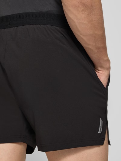 Männermodel trägt schwarze Regular Fit Shorts mit Logo-Print von PUMA PERFORMANCE, elastischer Bund, Eingrifftaschen, Nahaufnahme Oberkörper.