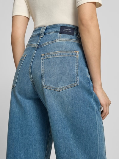 Kobiece model prezentuje jeansy aus Baumwoll-Mix in verkürzter Passform von Lanius, niebieskie, krój tapered fit, 5 kieszeni, zapięcie na guzik i zamek błyskawiczny, Szerokość w rozmiarze 36: 38 cm, Długość wewnętrzna nogawki w rozmiarze 36: 73 cm, widok na całe plecy.