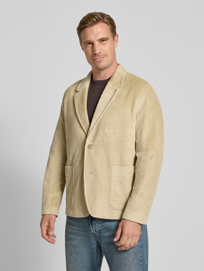 Männermodel trägt Sakko mit aufgesetzten Eingrifftaschen Modell 'YACODA' von DRYKORN, beige Farbe, Cordstruktur, Ganzkörperansicht von vorne, Baumwoll-Mix mit Stretch-Anteil, Regular Fit, Reverskragen, Knopfleiste, KI-modifiziertes Bild.