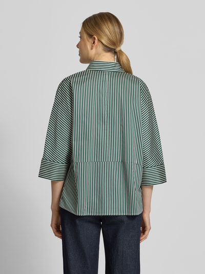 Frauenmodel trägt Regular Fit Hemdbluse mit durchgängiger Knopfleiste von Christian Berg Woman, weiß-grüne Streifen, reine Baumwolle, Halbarm, Ganzkörperansicht Rückansicht