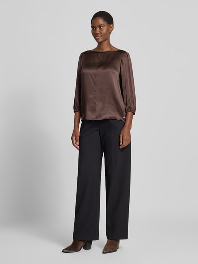 Frauenmodel trägt Regular Fit Bluse aus Seide mit 3/4-Arm von Marc Cain in Braun, kombiniert mit schwarzen Hosen, glatte Textur, Ganzkörperansicht von vorne. Reine Seide, Rundhalsausschnitt, Rückenlänge bei Größe 36: 59 cm, Ärmellänge bei Größe 36: 49 cm.