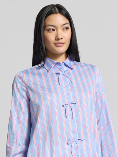 Frauenmodel trägt Regular Fit Hemdbluse aus reiner Baumwolle von Milano Italy mit Streifenmuster und Zierschleifen, Nahaufnahme Oberkörper. Damen Hemdbluse mit Hemdblusenkragen, durchgehender Knopfleiste, langärmliges Design, Rückenlänge 60 cm, Ärmellänge 61 cm.