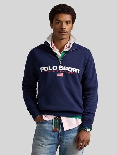 Männermodel trägt Relaxed Fit Troyer aus Baumwoll-Mix von Polo Ralph Lauren in Dunkelblau mit Label Print, langer Reißverschluss, Sweat-Struktur, Ganzkörperansicht von vorne.