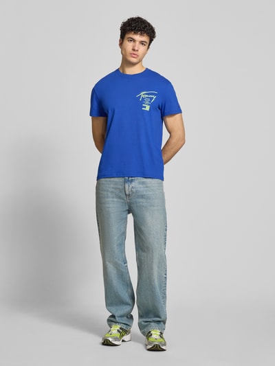 Männermodel trägt Regular Fit T-Shirt aus reiner Baumwolle von Tommy Jeans in Optik: Unifarben, Jersey, Label-Schriftzug, Ganzkörperansicht von vorne.