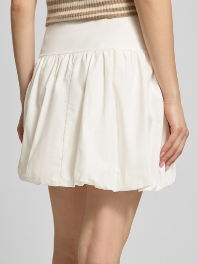 Frauenmodel trägt Bubble Skirt mit seitlichem Reißverschluss Modell 'Elou' von OH APRIL aus Reine Baumwolle, ausgestellter Schnitt, Minirock, Cremefarbe, glatte Textur, Bundweite bei Größe S 35 cm, Gesamtlänge 40 cm, Ganzkörperansicht Rückansicht.