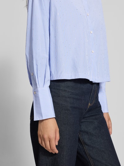 Frauenmodel trägt Relaxed Fit Hemdbluse mit Strasssteinbesatz von MANGO, blau-weiß gestreift, Baumwoll-Mix, Nahaufnahme Oberkörper.