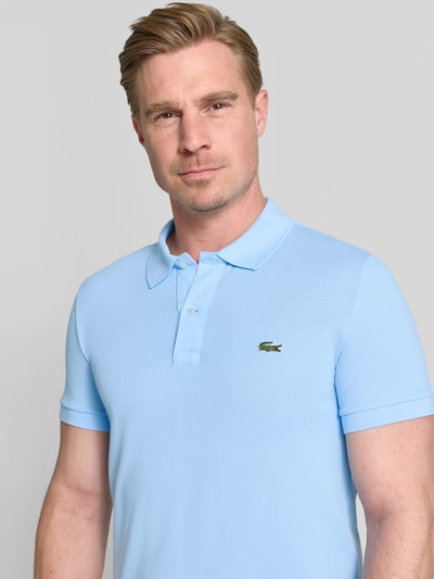 Männermodel trägt lichtblauw slim fit poloshirt van puur katoen Slim Fit Poloshirt aus reiner Baumwolle van Lacoste, Nahaufnahme Oberkörper.