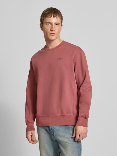 Männermodel trägt Sweatshirt mit Logo-Stitching und Rundhalsausschnitt von Levi's®, gewachste Baumwolle, lockerer Schnitt, Ganzkörperansicht von vorne.