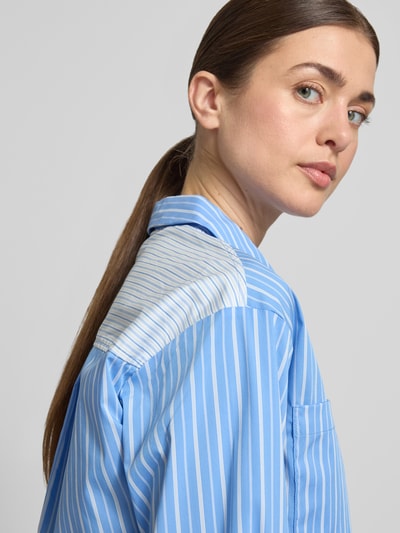Vrouwenmodel draagt blouse met borstzakken model 'Dana' van GUIDO MARIA KRETSCHMER WOMAN in blauw-witte strepen, katoenmix met stretch, regular fit, overhemdkraag, knoopsluiting, sportmanchetten, detailopname schouder en borst.