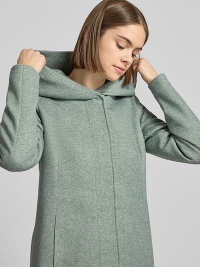 Modelka kobieca nosi taillierter Mantel mit Kapuze Modell 'SEDONA' od Only, kolor melanżowy, krój taliowany, długi rękaw, zapięcie na ukryte napy i zamek, boczne kieszenie, jednolita struktura, zbliżenie na górę ciała.