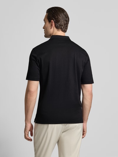 Męski model nosi Regular Fit Poloshirt mit Brusttasche von Christian Berg Men, czarny bawełniany materiał, krój regular fit, widok całej sylwetki z tyłu.