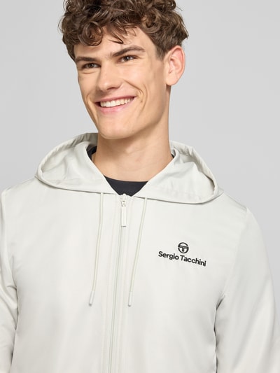 Männermodel trägt Regular Fit Tracksuit mit Logo-Stitching Modell 'Carson' von SERGIO TACCHINI in Hellgrau, Nahaufnahme Oberkörper.
