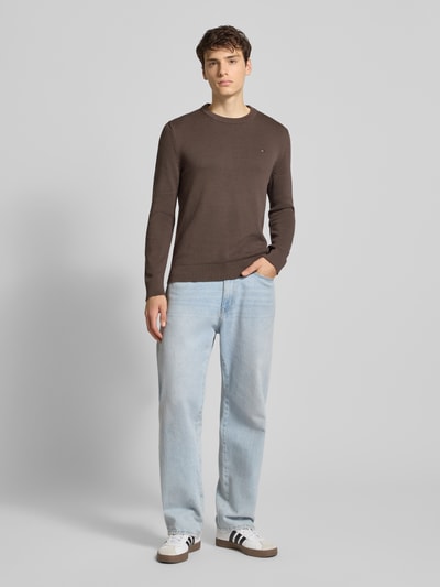 Męski model nosi Regular Fit Strickpullover aus reiner Baumwolle od Tommy Jeans, jednolity, bawełna, logo, długi rękaw, krój regular fit, widok całej sylwetki z przodu.