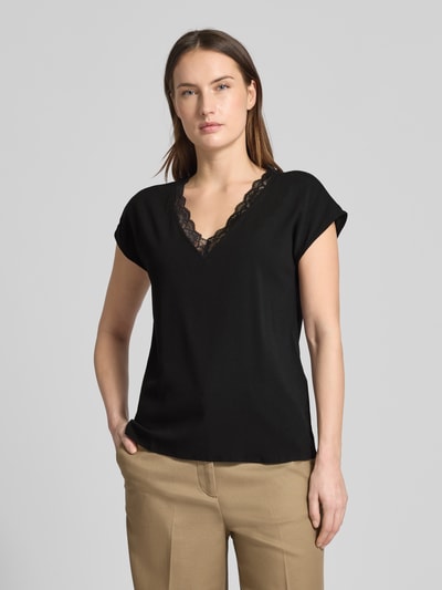 Modelka kobieca prezentuje Regular Fit T-Shirt mit Spitzenkragen Modell 'BELLA' od Vero Moda, czarny, jersey stretch, krój regular fit, krótki rękaw, V-dekolt z koronką, bawełna i wiskoza, widok na górną część ciała z przodu.