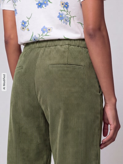 Frauenmodel trägt Straight Fit Cordhose mit elastischem Bund Modell 'CHIARA' von MAC in Olivgrün, feine Cordstruktur, Nahaufnahme Rückansicht, Damen Cordhose von MAC, KI-modifiziertes Bild.