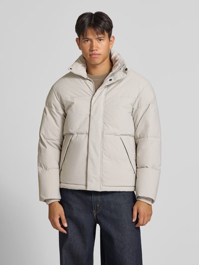 Männermodel trägt lichtbeige gewatteerd jack met opstaande kraag en ritssluiting, Model 'SOHO' van JACK & JONES, regular fit, Ganzkörperansicht von vorne. Ruglengte bij maat M 70 cm, schouderbreedte 47 cm, borstwijdte 60 cm, mouwlengte 68 cm.