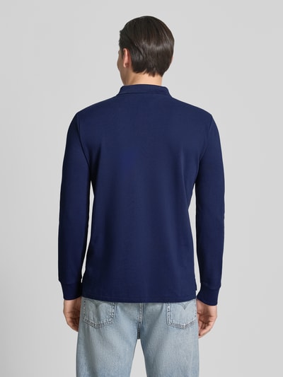 Männermodel trägt Regular Fit Poloshirt aus reiner Baumwolle von Polo Ralph Lauren, unifarbenes Dunkelblau, Piqué, Ganzkörperansicht Rückansicht.