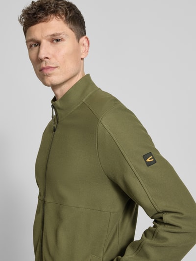 Männermodel trägt Sweatjacke mit Stehkragen und Reißverschluss von camel active in Olivgrün, reine Baumwolle, Nahaufnahme Oberkörper.