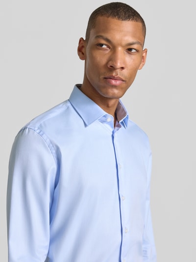 Mężczyznamodel nosi Slim Fit Business-Hemd mit Kentkragen von Jake*s z bawełny, jasnoniebieski kolor, listwa guzikowa, sportowe mankiety, zaokrąglony dół, długość tyłu w rozmiarze 39/40: 79 cm, szerokość w rozmiarze 39/40: 48 cm, długość rękawów w rozmiarze 39/40: 65 cm, krój slim fit, kołnierzyk typu kent, gładka tekstura, zbliżenie na górną część ciała