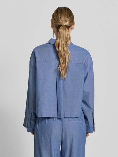Männermodel trägt Cropped Bluse aus reiner Bio-Baumwolle Modell 'KIRA-ASTHA' von Selected Femme w tkaninie stylizowanej na denim, krój krótki, kołnierzyk koszulowy, listwa guzikowa, długi rękaw, brustasza, materiał: bawełna ekologiczna, widok całej sylwetki z tyłu.