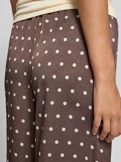 Frauenmodel trägt Stoffhose im Allover-Look Modell 'Sebba' von Neo Noir aus Satin mit weißem Punktmuster, Relaxed-Fit, Detailaufnahme Rückansicht. Bundweite 37 cm, Innenbeinlänge 76 cm bei Größe 36.