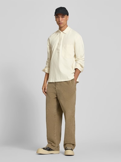 Männermodel trägt Regular Fit Poloshirt mit Brusttasche von Officine Générale in Creme, reine Baumwolle, Polokragen, lange Ärmel, Ganzkörperansicht von vorne.