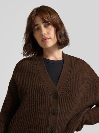Frauenmodel trägt Strickjacke aus Alpaka-Mix mit V-Ausschnitt von Closed, braun, strukturierte Oberfläche, Relaxed Fit, Nahaufnahme Oberkörper.