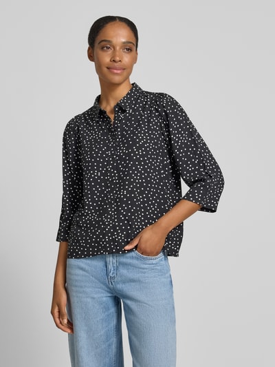 Frauenmodel trägt Regular Fit Bluse aus reiner Viskose mit 3/4-Arm Modell 'Bono' von LOLLYS LAUNDRY, Allover-Look, Hemdblusenkragen, Knopfleiste, schwarze Grundfarbe mit weißen Punkten, glatte Struktur, Rückenlänge 60 cm, Ärmellänge 45 cm, Ganzkörperansicht von vorne.