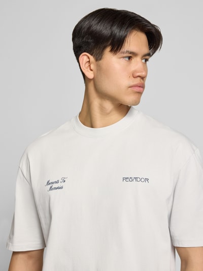 Männermodel trägt Oversized T-Shirt mit 1/2-Arm Modell 'Zernez' von Pegador aus Reine Baumwolle mit Rundhalsausschnitt, Label-Detail, Nahaufnahme Oberkörper.