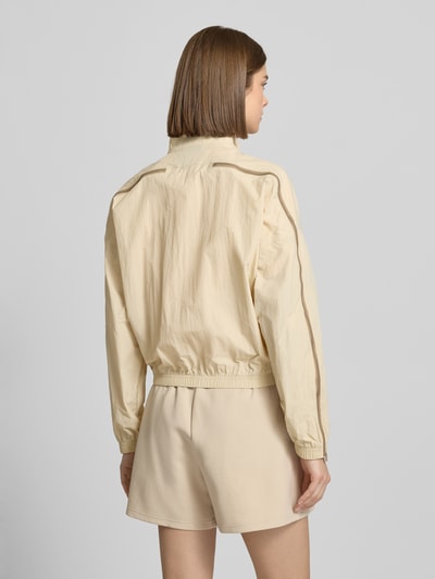 Vrouwenmodel draagt Jacke mit Stehkragen van adidas Sportswear in beige met regular fit, elastische boorden en label-print, rugaanzicht
