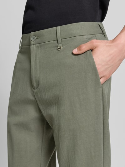 Männermodel trägt Anzughose mit Aufschlag Modell 'ASHE' von Antony Morato aus Leinen-Baumwoll-Mix in Oliv, Nahaufnahme Oberkörper. Slim-Fit, Knopf-Reißverschluss, französische Eingrifftaschen, Gesäßleistentaschen, Struktur im Anzug-Stoff:, Bundweite bei Größe 50: 43 cm, Innenbeinlänge 74 cm.