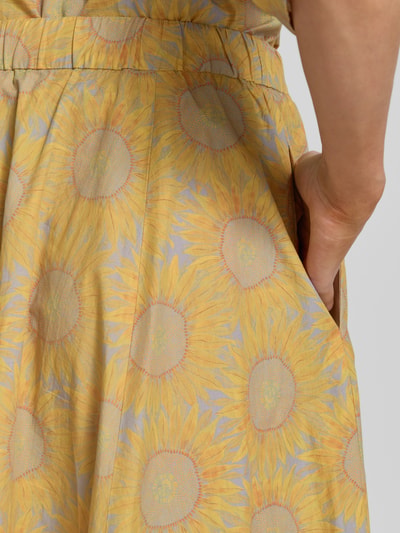 Vrouwenmodel draagt Midirock met Eingrifftaschen van Drykorn in gele en paarse zonnebloemprint, katoen, detailopname heup.