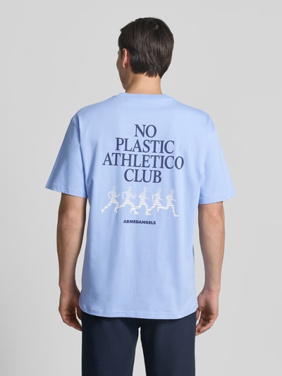 Männermodel trägt Relaxed Fit T-Shirt aus reiner Baumwolle Modell 'MAARKOS' von Armedangels in Hellblau mit Logo-Print auf glatter Jersey-Oberfläche, Ganzkörperansicht Rückansicht.